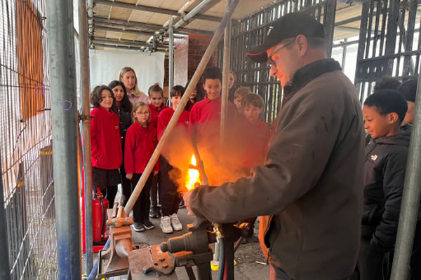 The blacksmith shows the children the effect of decreasing oxygen on the flame