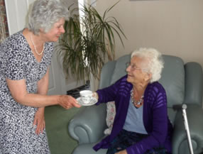 Elderly person being given a cup of tea 