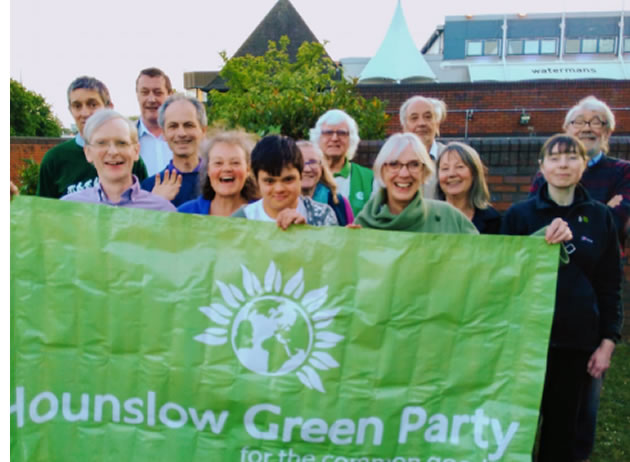 the green party members hold up an election banner 