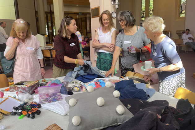 A group discusses sewing repairs at the coffee morning