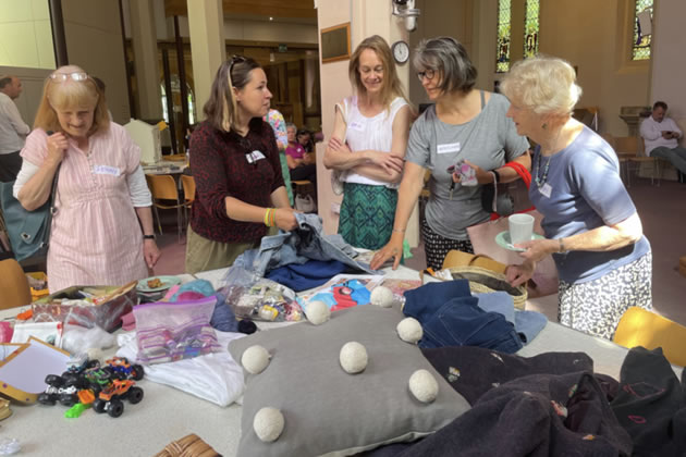 A group discusses sewing repairs at the coffee morning 