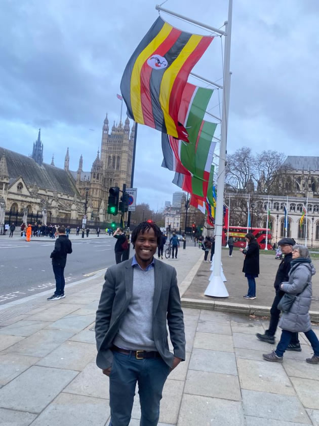 Cllr Mushiso in front of the Ugandan flag 
